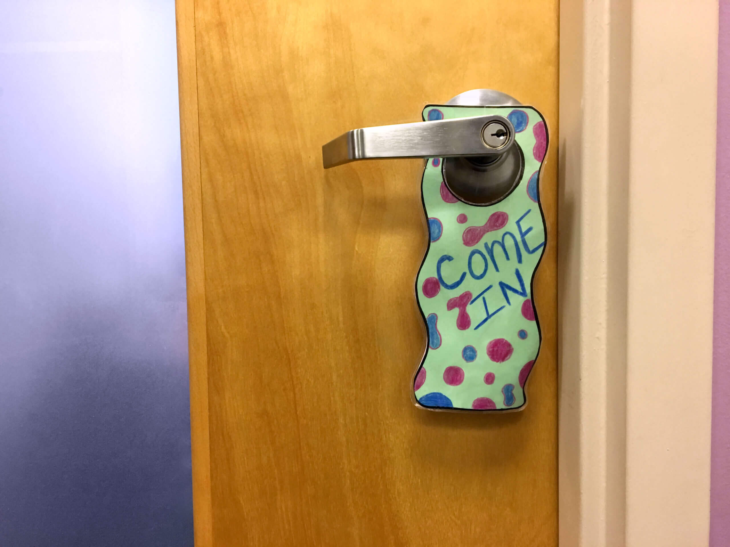A sign saying "Come in" hanging on a door at Safe Shores