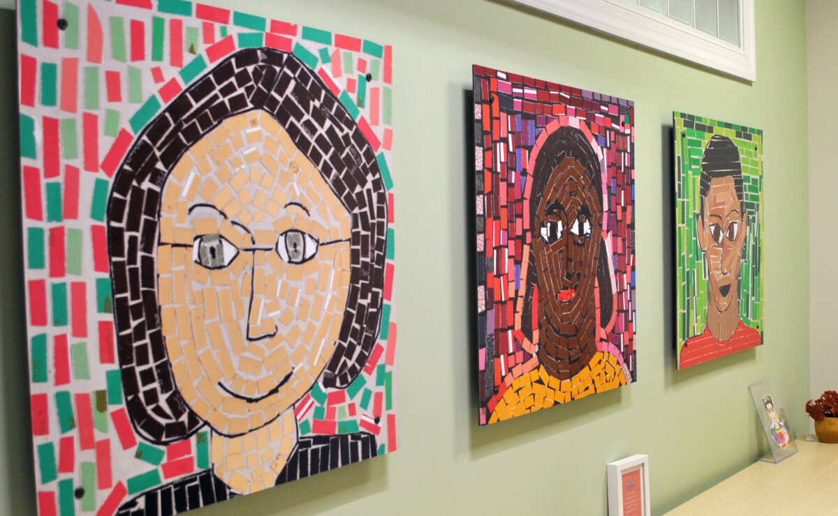 Three canvases with self-portrait mosaic art by children at the Safe Shores building