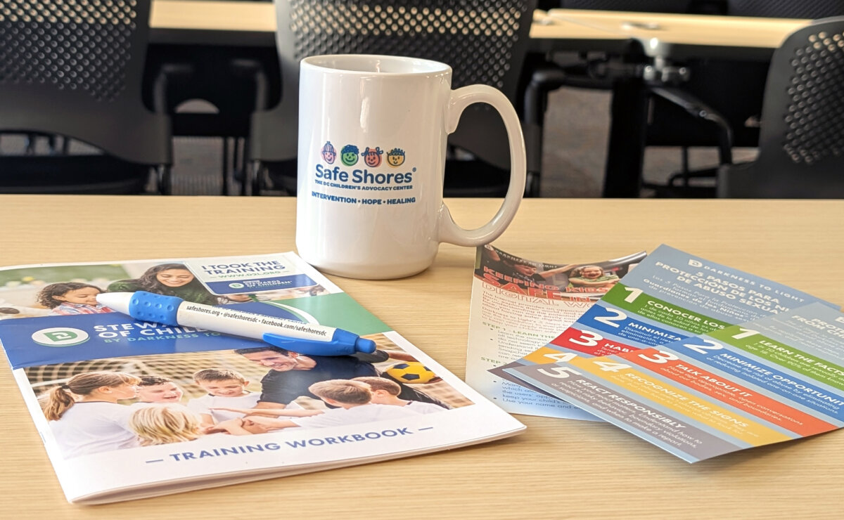 Training workbooks and a Safe Shores mug sitting on a desk